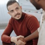 Two professionals shaking hands during a business meeting indoors.