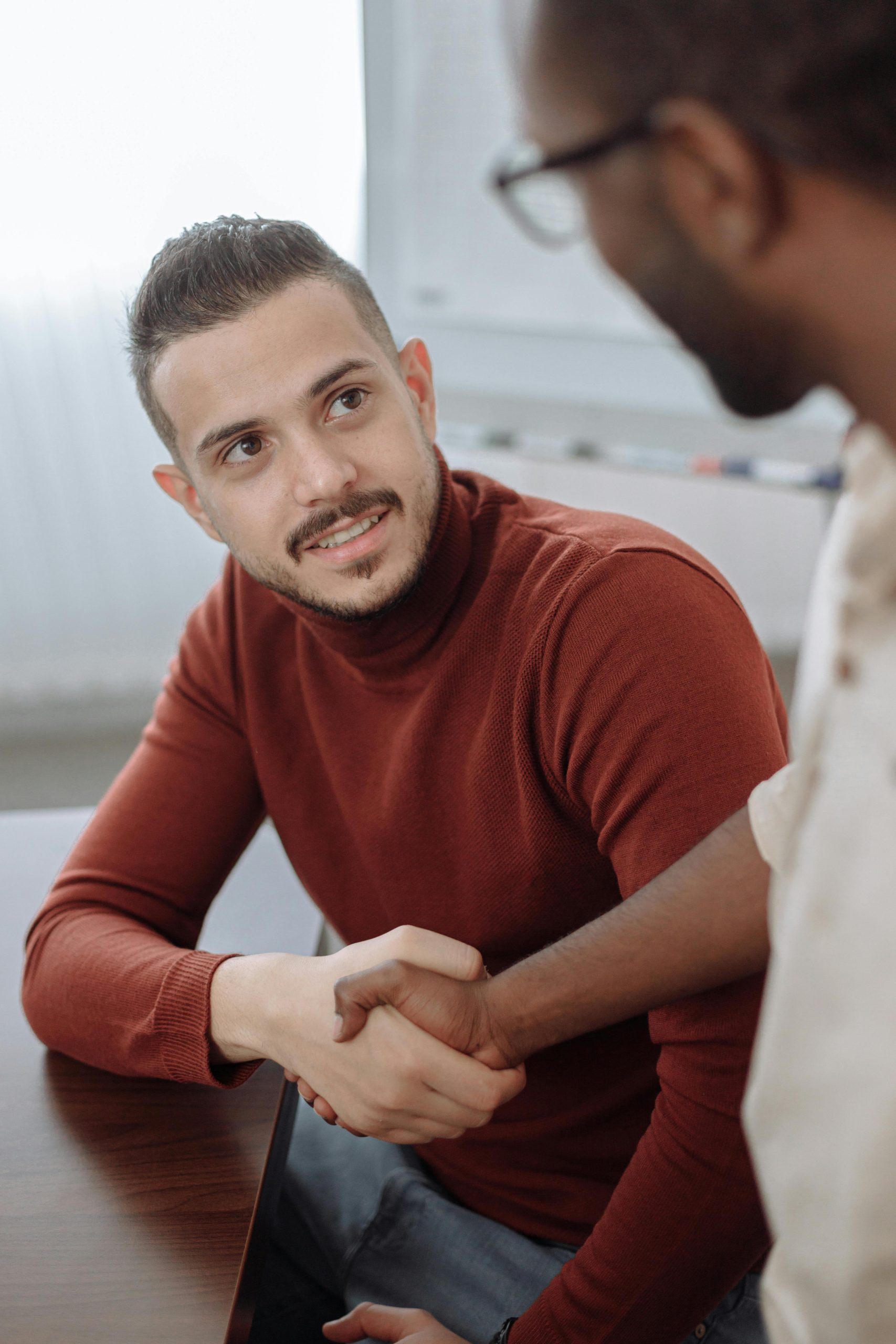 Two professionals shaking hands during a business meeting indoors.