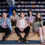 A group of diverse teenagers sitting in a library, showcasing youth diversity and style.