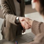 Two professionals shaking hands in an office, signifying a successful business agreement.
