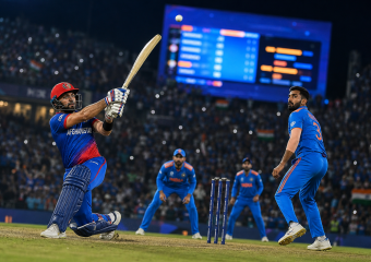 Afghanistan batter plays a shot as Indian players field during a night cricket match