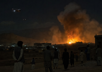 People watch a large fire and plume of smoke over a city at night as two aircraft fly overhead